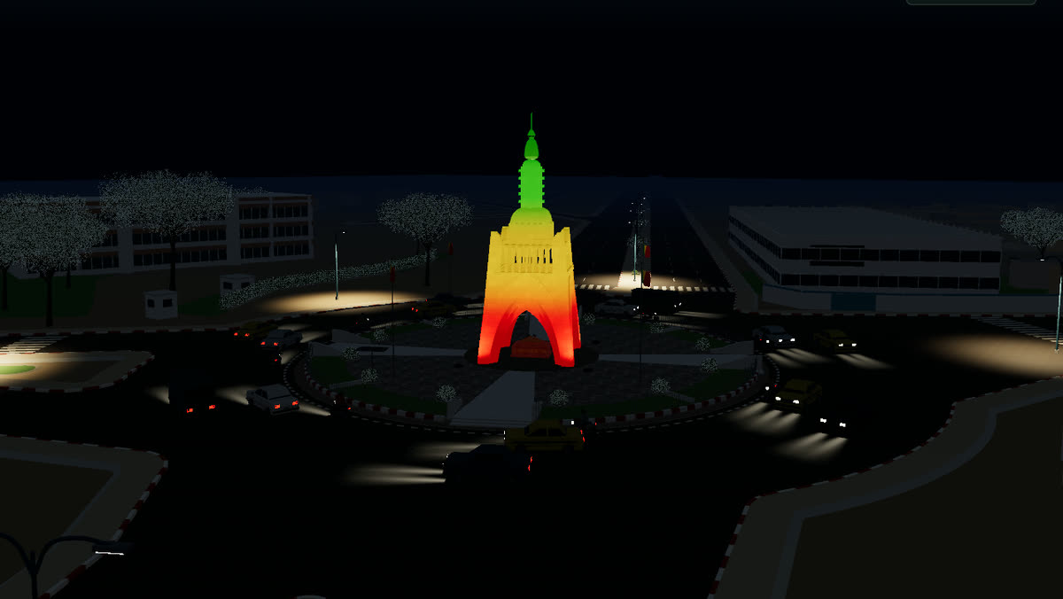 The 3D Monument de l'Indépendance at night, lit in green, yellow and red.